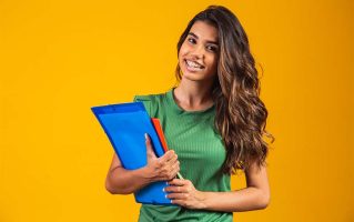 smiling-woman-student-with-school-books-hands-yellow-background